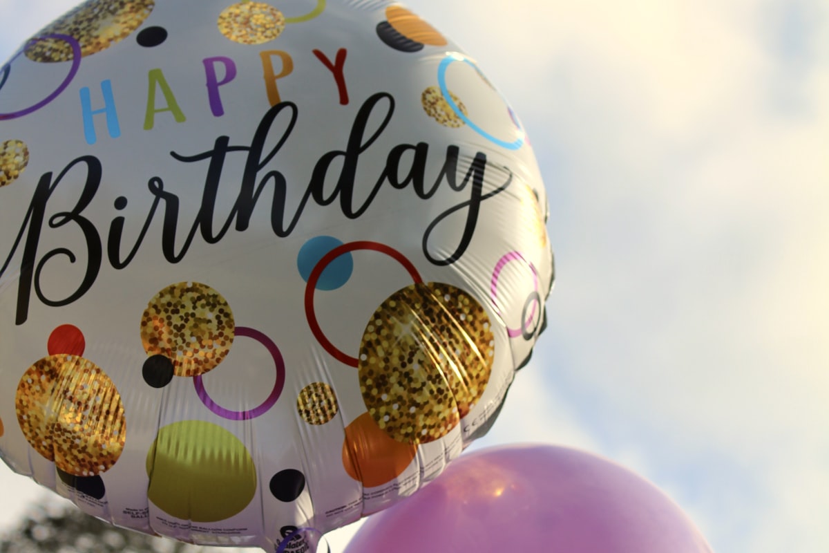 Person writing a birthday card with decorations on the table
